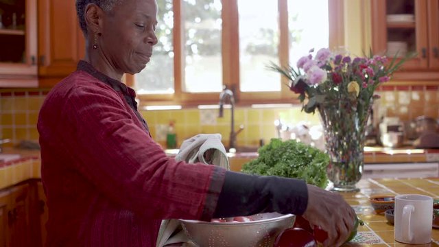 Medium shot of a happy senior black woman drying off a red apple in 4k