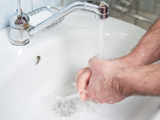 Hygiene concept. Washing hands with soap under the faucet with water. Coronavirus protection.