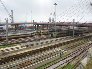 Trains in transit on the tracks in the background a bridge and cleaners.