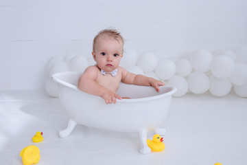 Little boy takes a bath. Water treatments with yellow ducks.