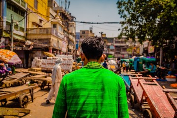 Closeup selective focus shot of a man in a green shirt walking in an Indian market