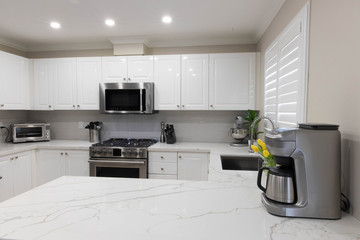 Modern Kitchen with new white quartz countertops with gray veining and stainless steel appliances.
