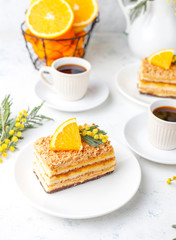Orange cake decorated with fresh orange slices and mimosa flowers on light background