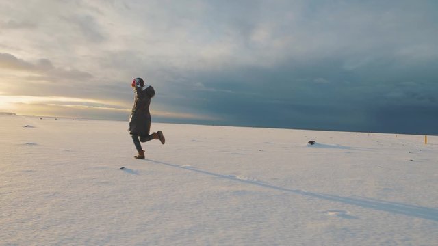 Hipster woman traveler running on snow desert in Iceland at sunset or sunrise. Around Solheimasandur dc3 Plane crash area 