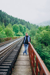 Young man in jeans on a railway track. Man in the mountains