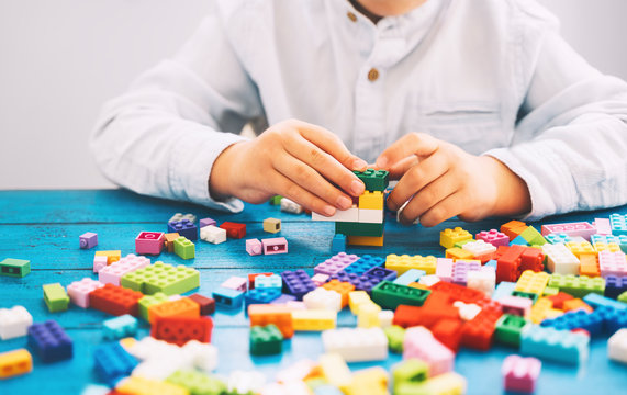 Child playing and building with colorful toy bricks, plastic blocks.