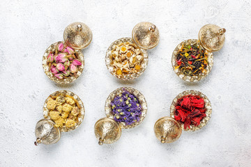 Assortment of dry tea in golden vintage mini plates.Tea types background:hibiscus,chamomile,mixed black tea,dry roses,butterfly pea tea