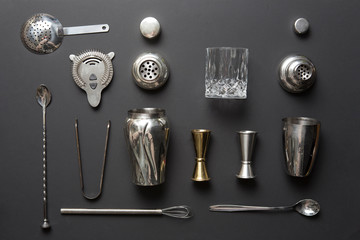 Flat lay composition with bartender iron tools, such as cocktail shaker, jigger, mixing glass,...