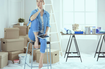 Young woman sitting on a white chair in an empty room, thinking on something