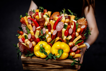 Basket with vegetables and sausages in girl hands.