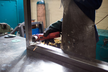 Close up image of an industrial worker working with an angle grinder
