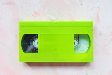 Green vintage VHS video tape on pink. Retro minimalist background, copy space