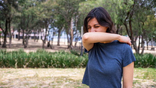 mujer joven estornudando en codo
