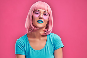 Photo close up view of sexual charming woman with pink hair wearing trendy sunglasses looking at camera with fashion look isolated over pink background