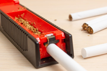machine for filling cigarettes with tobacco and cigarettes on a light tree