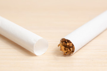 one cigarette with tobacco and the other without on a light wooden