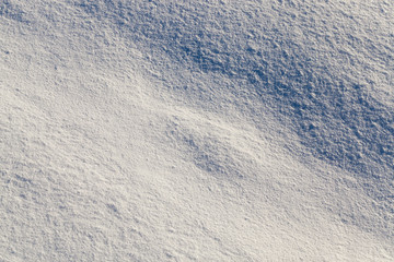 land covered with snow - white snow after snow had fallen and covered the land in the agricultural field. Photo closeup in the winter season, a small depth of field. On visible surface roughness snow