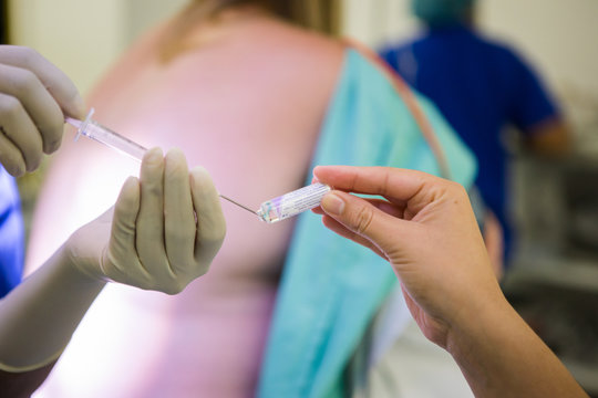 Close up image of a doctor performing a epidural spinal block for a pregnant woman