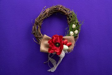 An easter decorative wreath with a flower, eggs and a ribbon on a dark purple surface
