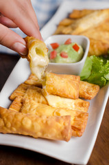 hand holding cheese sticks with guacamole dip