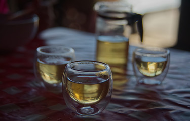 An oval transparent tea glass cup with blur tea set background