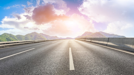 Empty asphalt road and green mountain nature landscape at sunset.