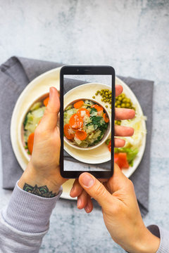 Smartphone food photography for lunch or dinner. Making lifestyle photo of steamed boiled vegetables with phone. Concept for social media blogging and online order services. Vegan and vegetarian diet.