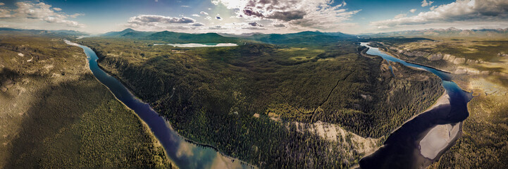 Drone aerial view of Yukon Territory wilderness with river running along the whole panoramic shot...