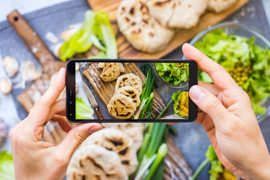 Smartphone food photography for lunch or dinner. Making lifestyle photo of stuffed bread cakes with phone. Concept for social media blogging and online order services. Vegan and vegetarian diet.