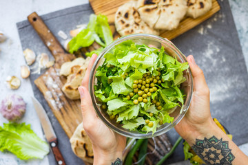 Woman holds green herbal leaves fresh detox salad in glass bowl in hands. Vegan, vegetarian healthy diet food