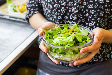 Woman holds green herbal leaves fresh detox salad in glass bowl in hands. Vegan, vegetarian healthy diet food