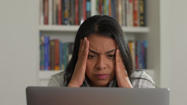 Close-up Of A Hispanic Or Asian Woman Is Sitting At Home In Front Of A Laptop Computer, Being Worried, Fearful And Frustrated