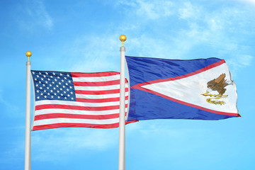United States and American Samoa two flags on flagpoles and blue cloudy sky