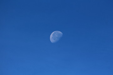 Clearly visible picture of Waning gibbous Moon phase on clear blue sky background taken early in...