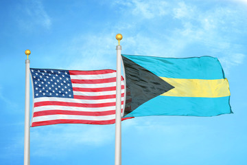 United States and Bahamas  two flags on flagpoles and blue cloudy sky