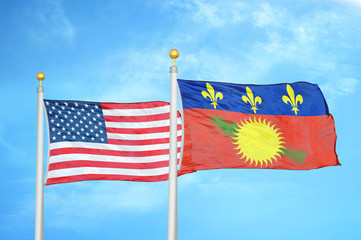 United States and Guadeloupe two flags on flagpoles and blue cloudy sky