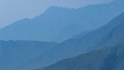 Fototapeta premium silhouettes of mountains in blue haze. Outline of gentle hills in the valley