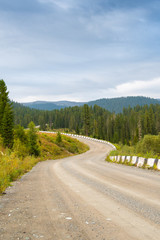 Fototapeta na wymiar bend dirt mountain road with stone safety barrier