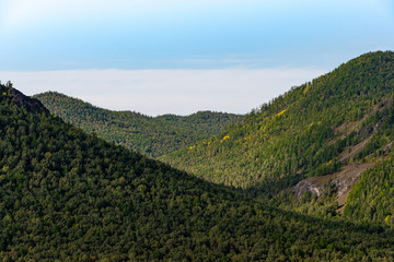 gentle green hills under blue cloudy sky, panorama of mountain landscape, valley for summer hiking