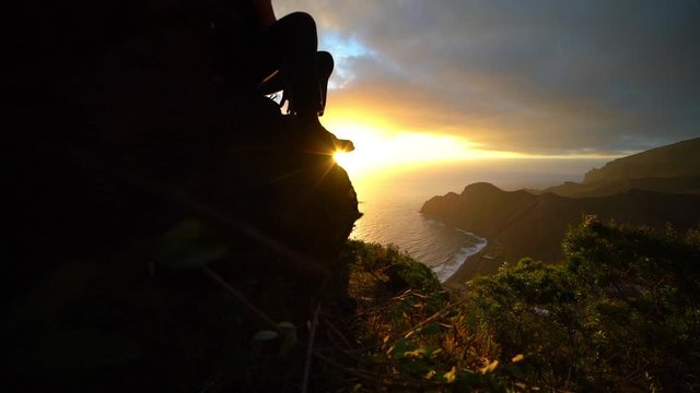 Man Sitting On Mountain Side And Watching Sun Rise