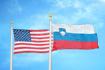 United States and Slovenia two flags on flagpoles and blue cloudy sky