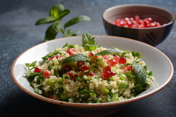 Healthy salad with couscous, fresh mint, cucumber, pomegranate, lemon and olive oil. Eastern cuisine. Vegan food concept. Traditional Israeli food