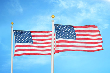 United States and United States two flags on flagpoles and blue cloudy sky