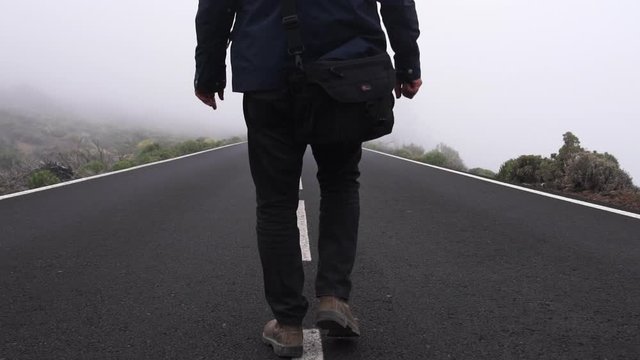 Man Walking Down Middle Of Empty And Misty Road