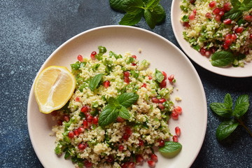Healthy salad with couscous, fresh mint, cucumber, pomegranate, lemon and olive oil. Eastern cuisine. Vegan food concept. Traditional Israeli food