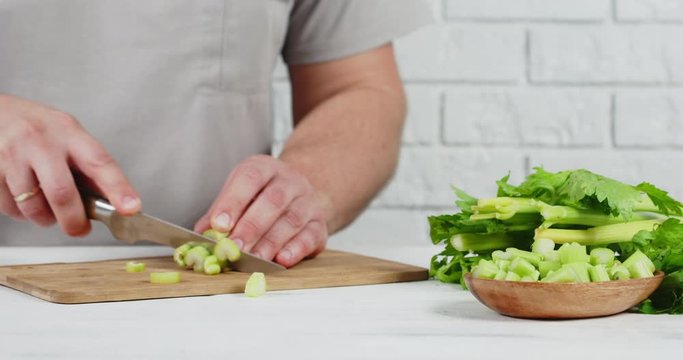Man cuts fresh celery on a cutting Board.