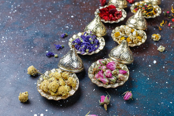 Assortment of dry tea in golden vintage mini plates.Tea types background:hibiscus,chamomile,mixed black tea,dry roses,butterfly pea tea