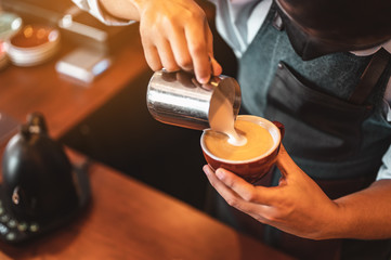Close-up of professionally extracting coffee by barista with a pouring steamed milk into coffee cup making beautiful latte art. coffee, extraction, deep, cup, art, barista concept.