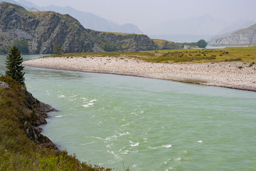 river in mountain valley, flow of water among rocks and stones with trees on shore, water tourist...