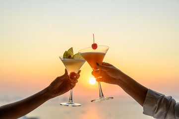 Couple enjoying of Cheers glass of cocktail in a restaurant  at sunset view sea. Cocktail, Couple,...
